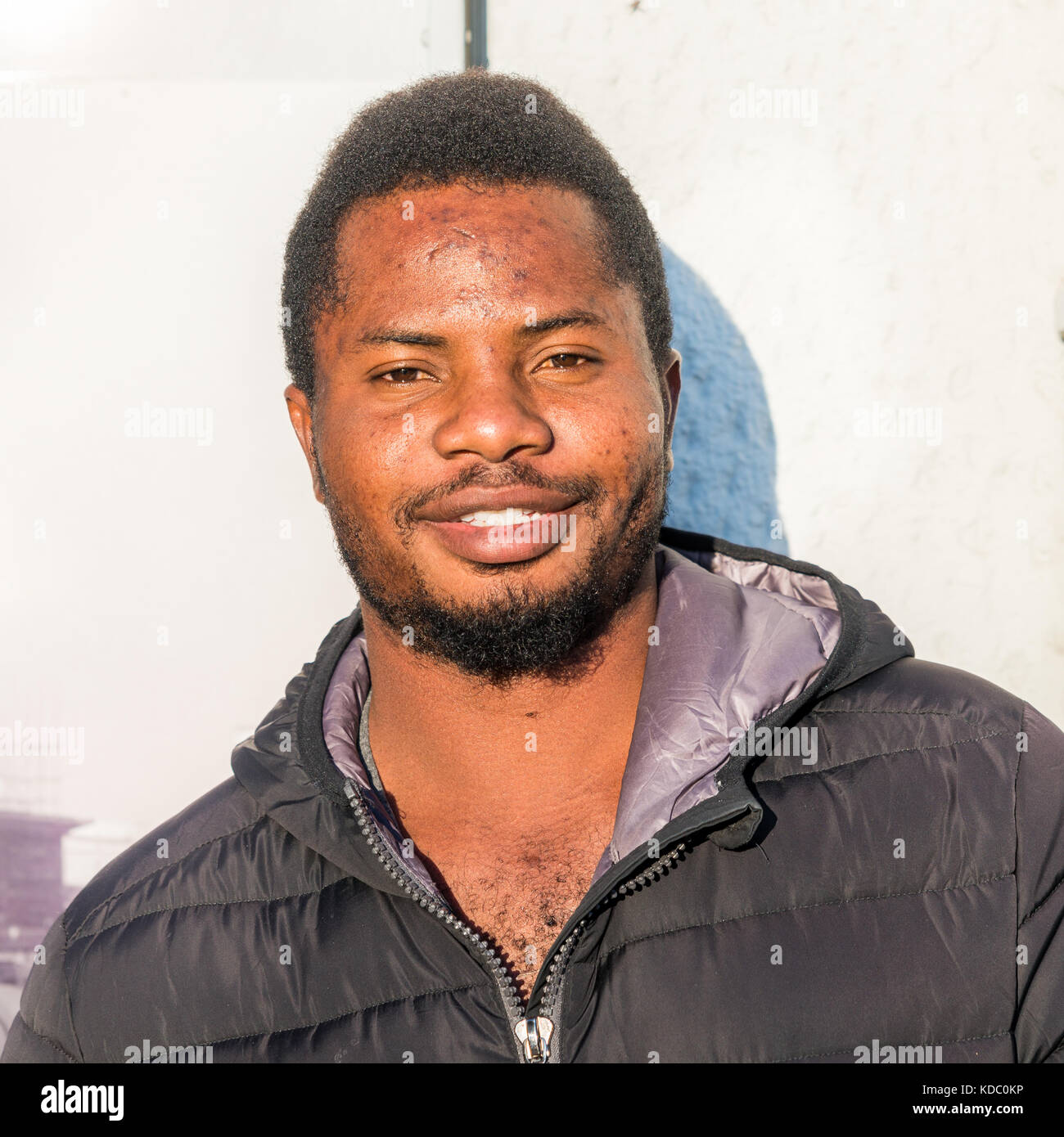 Portrait d'homme nigérian portant une veste noire contre un mur blanc, Italie. Banque D'Images