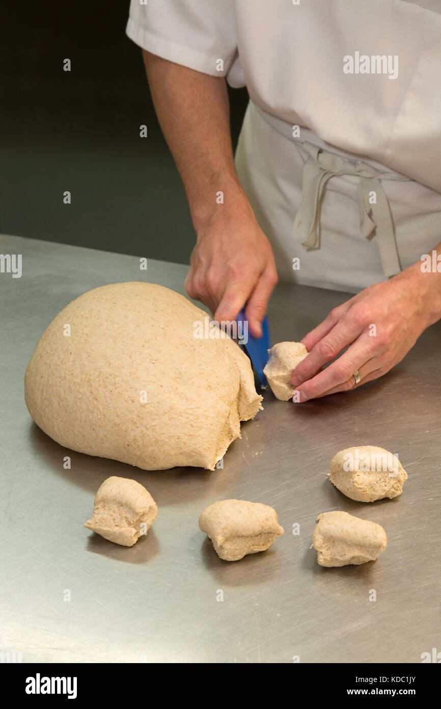Fabrication de pain - coupe de pâte pour faire de petits pains dans une boulangerie, Royaume-Uni Banque D'Images