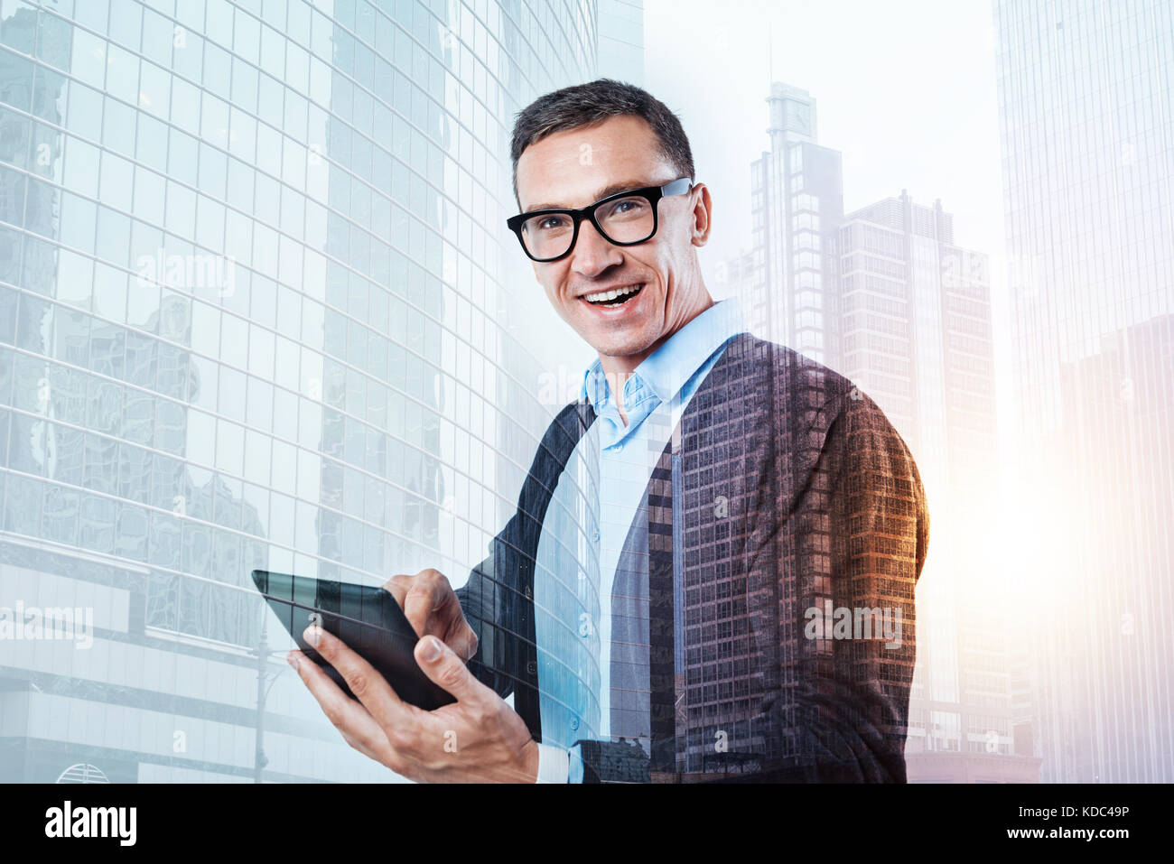 Heureux l'Homme à lunettes à la mode holding a tablet Banque D'Images