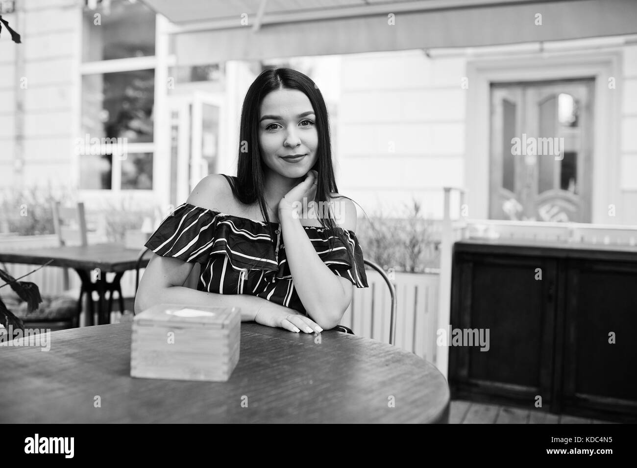 Superbe brune fille assise sur la table dans le café. Banque D'Images