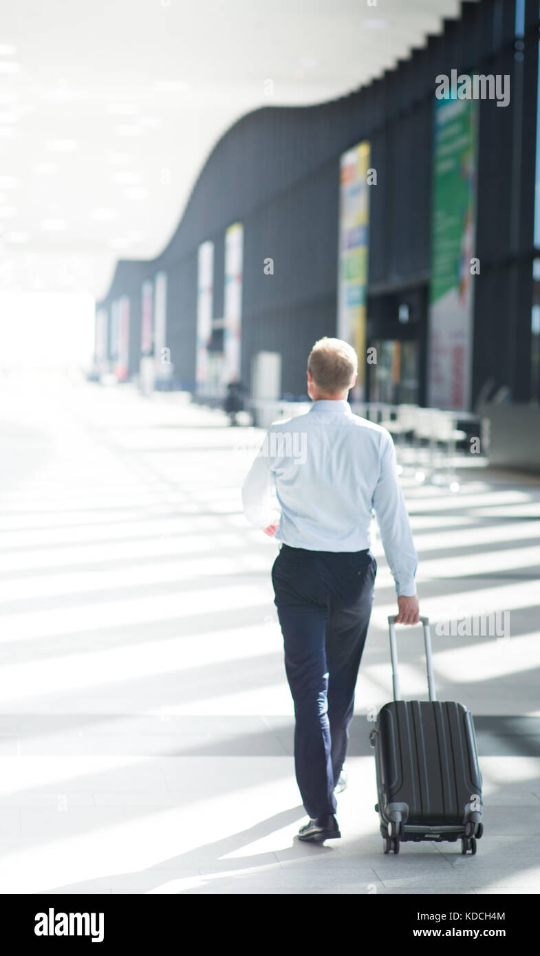 L'homme d'affaires dans l'Habillement formel la marche avec sac à roues à l'aéroport Banque D'Images