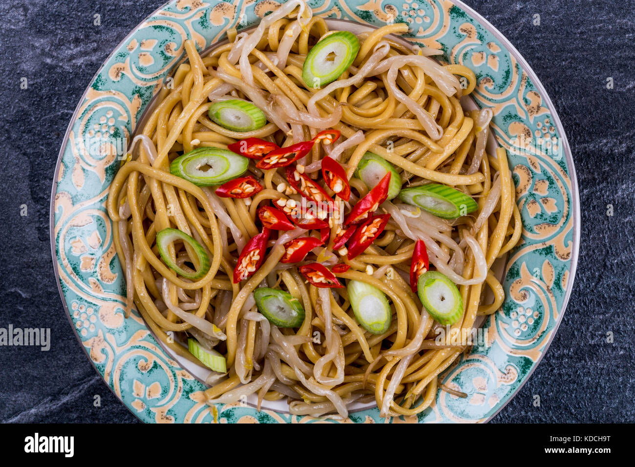 Style chinois nouilles aux oeufs sautées au wok avec des germes et red chili sur une tuile ardoise cuisine noire Banque D'Images