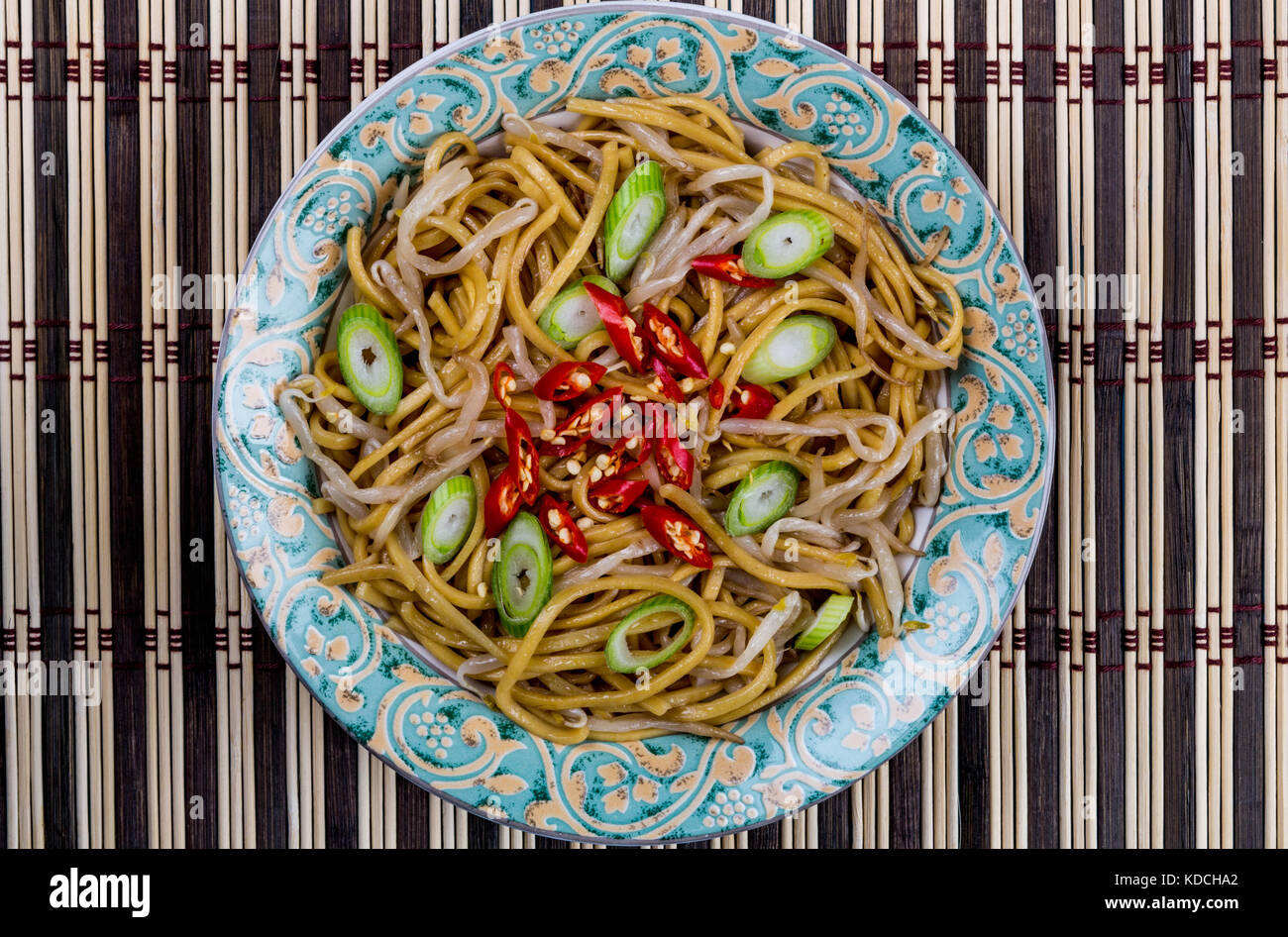 Style chinois nouilles aux oeufs sautées au wok avec des germes et red chili sur un tapis de table en bambou Banque D'Images