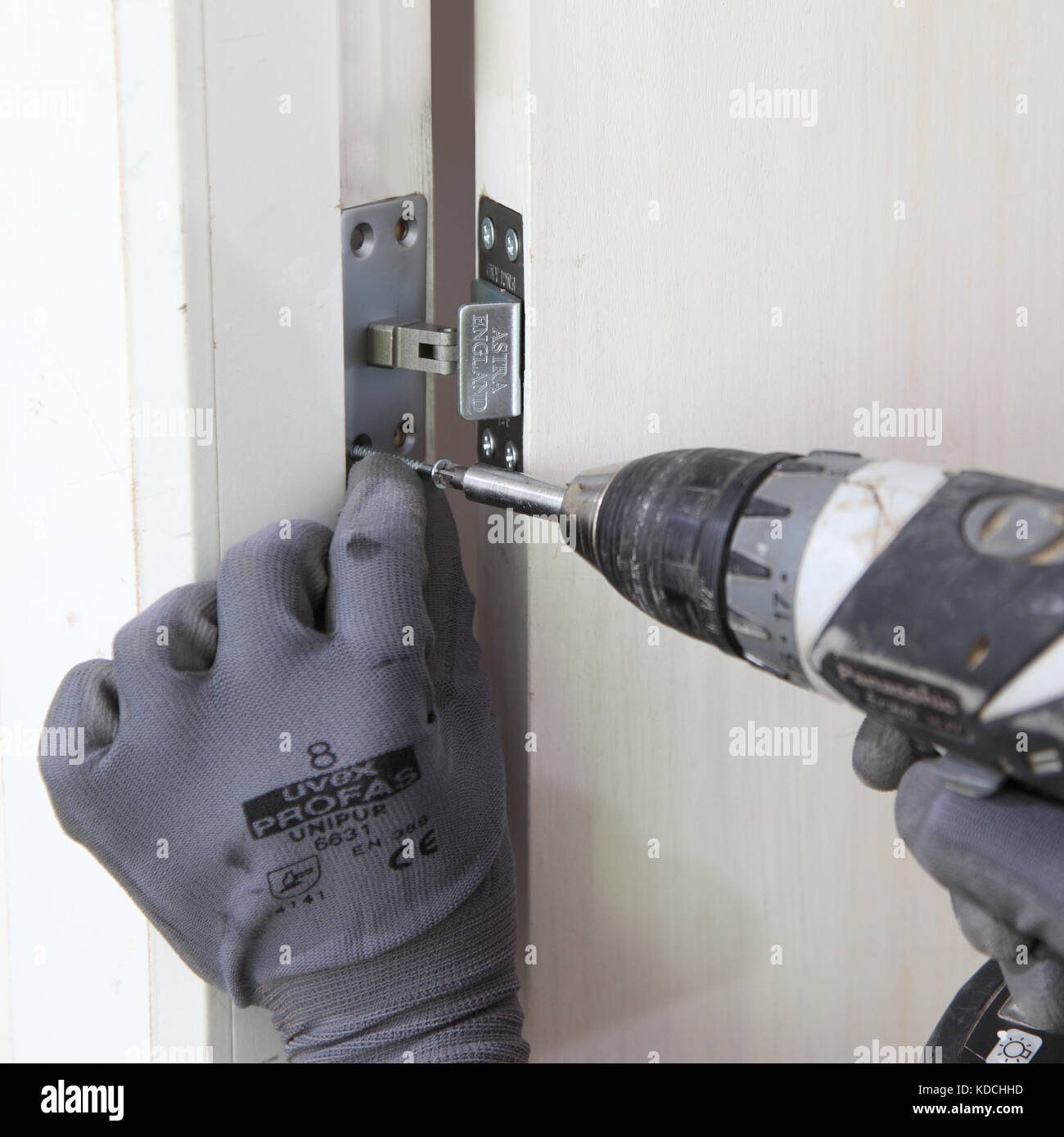 Un ouvrier installe un près dissimulé d'une nouvelle porte d'incendie dans le cadre de la rénovation d'un immeuble résidentiel à Londres, au Royaume-Uni. Banque D'Images