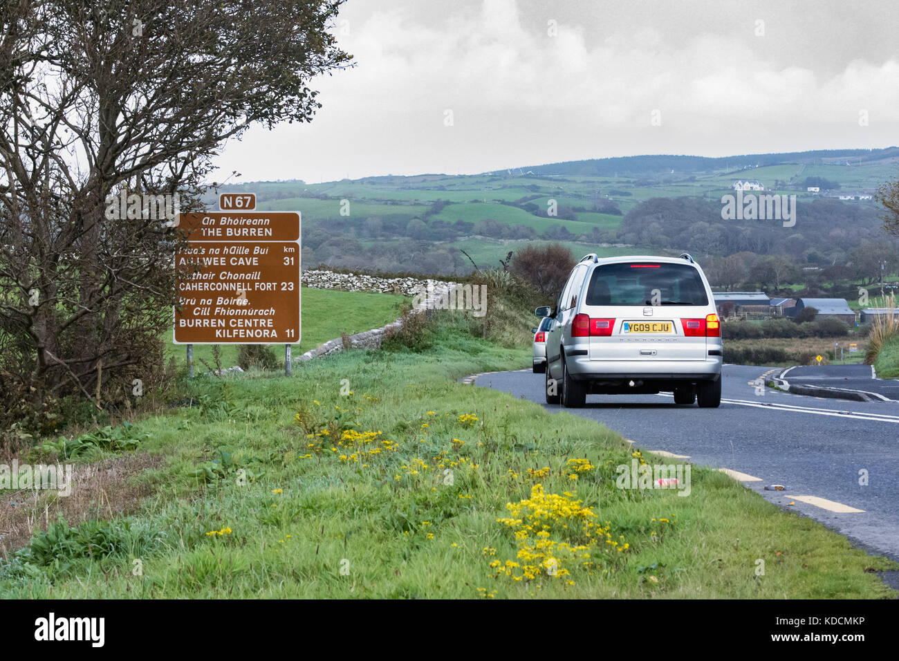 Voiture sur la route en passant par le Burren (comté de Clare, Irlande) avec panneau pour diverses destinations touristiques. Banque D'Images