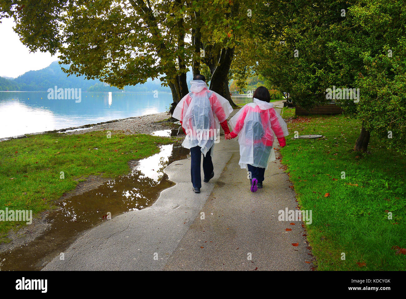 Un couple dans des imperméables à pied au bord du lac de Bled en Bled, en Slovénie. Banque D'Images