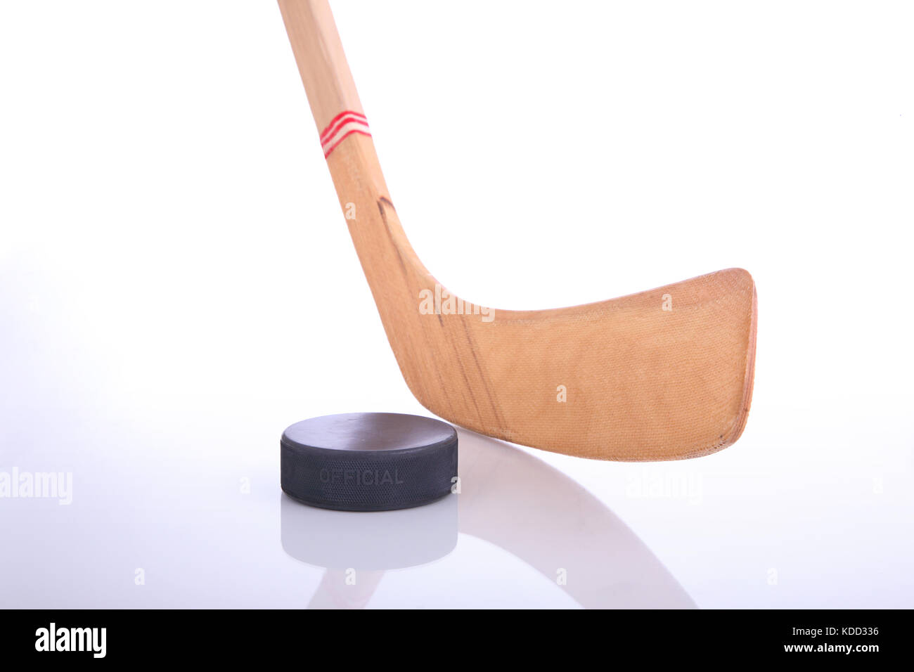 Bâton de hockey et puck on reflective surface avec un fond blanc Banque D'Images