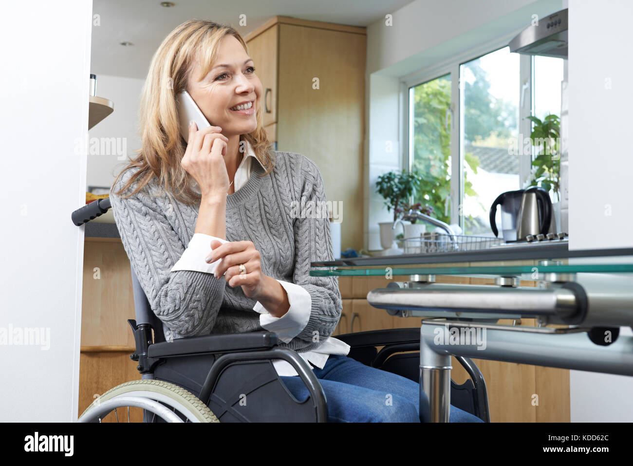 Mobilité woman in wheelchair talking on mobile phone at home Banque D'Images