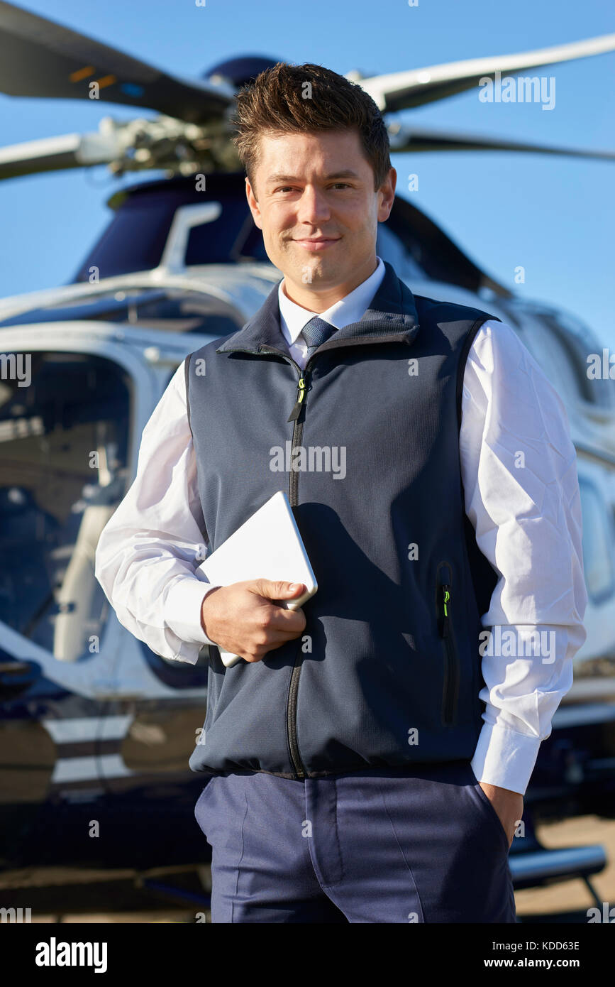 Portrait de pilot standing in front of helicopter with digital tablet Banque D'Images