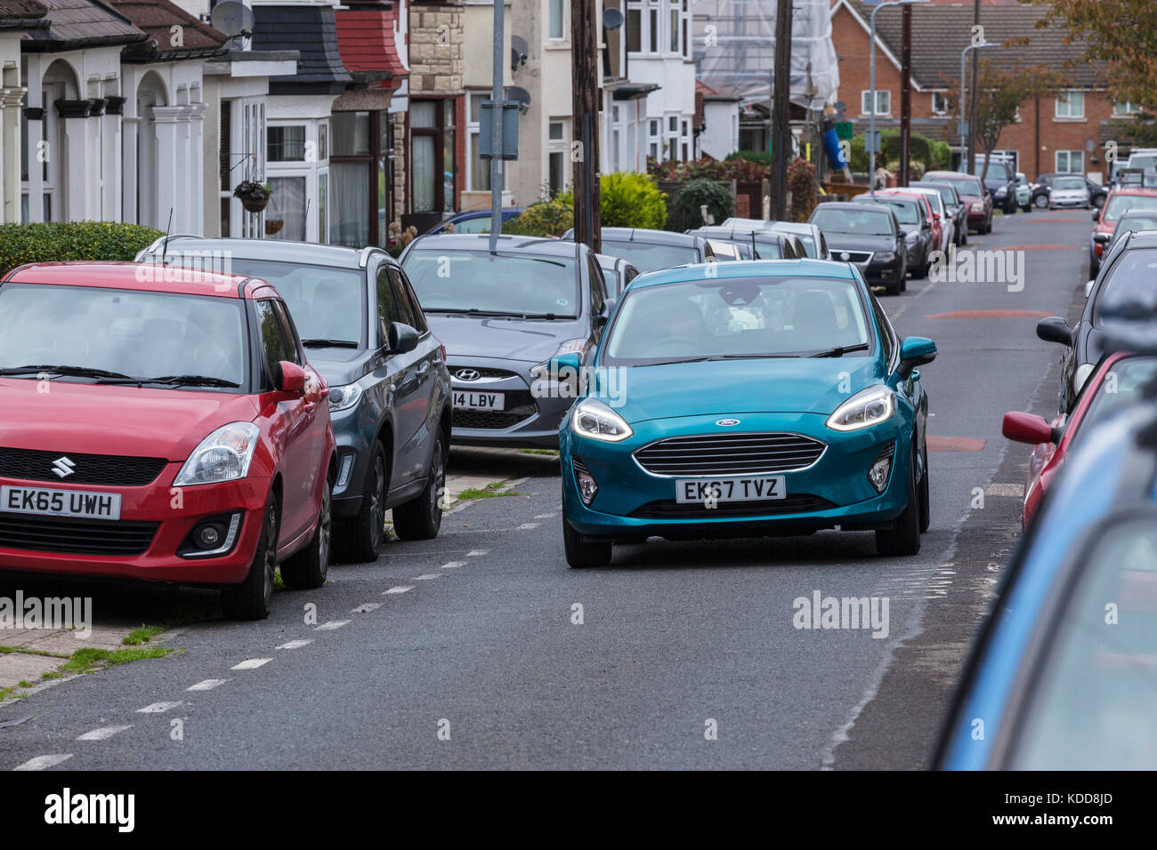 Ford Fiesta 2017 conduite sur route étroite avec d'autres voitures garées des deux côtés Banque D'Images