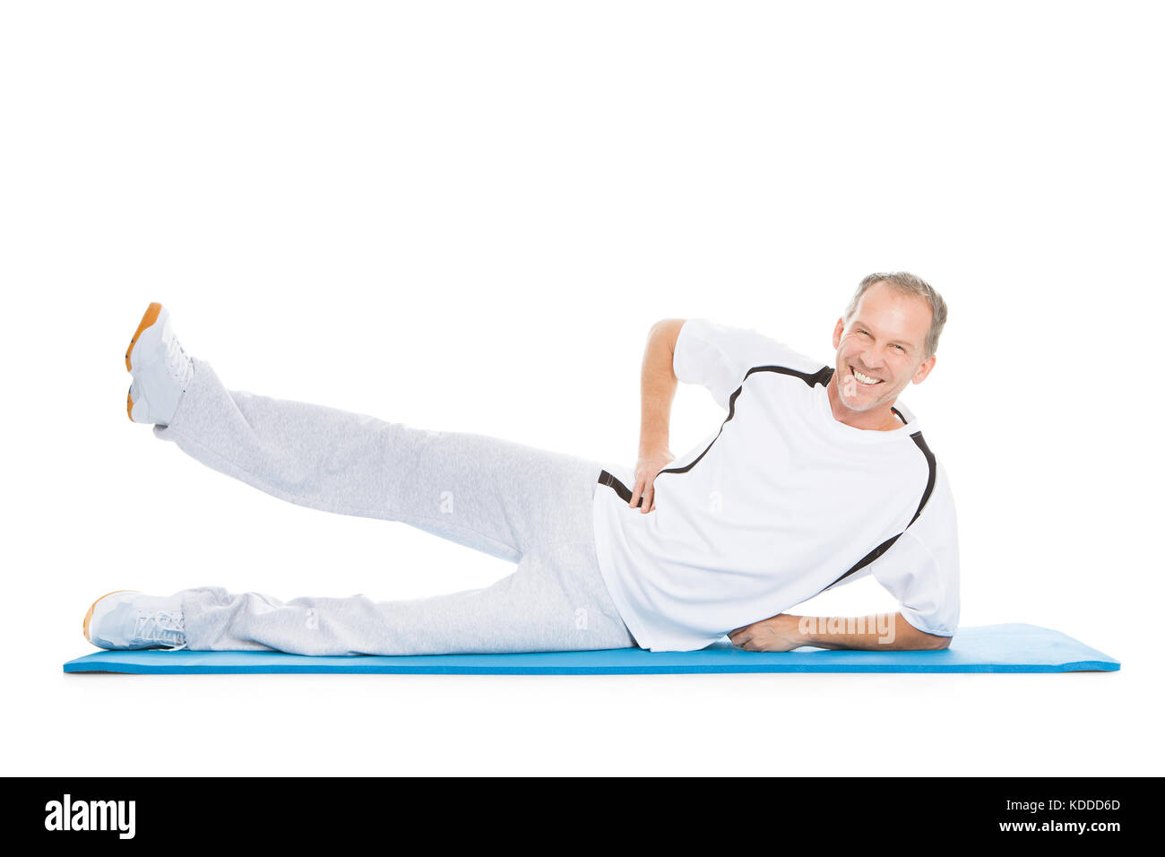 Portrait Of Mature Man Stretching Leg Lying On Exercise Mat Banque D'Images