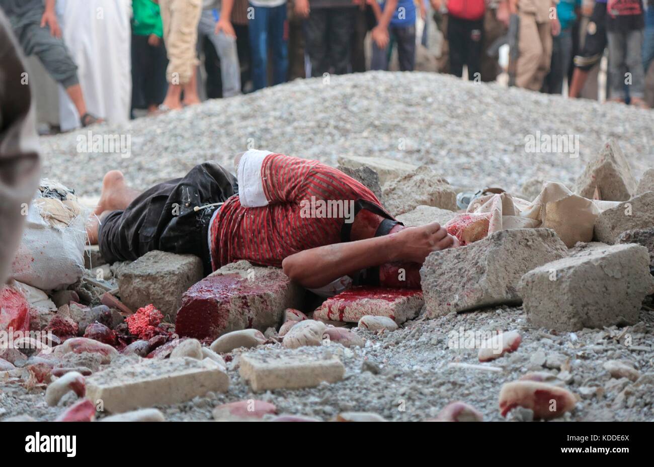 Note du rédacteur : contenu graphique. sans date de propagande isis image montrant un homme mort par lapidation pour sodomie lors d'une exécution publique de Raqqa, en Syrie. Banque D'Images