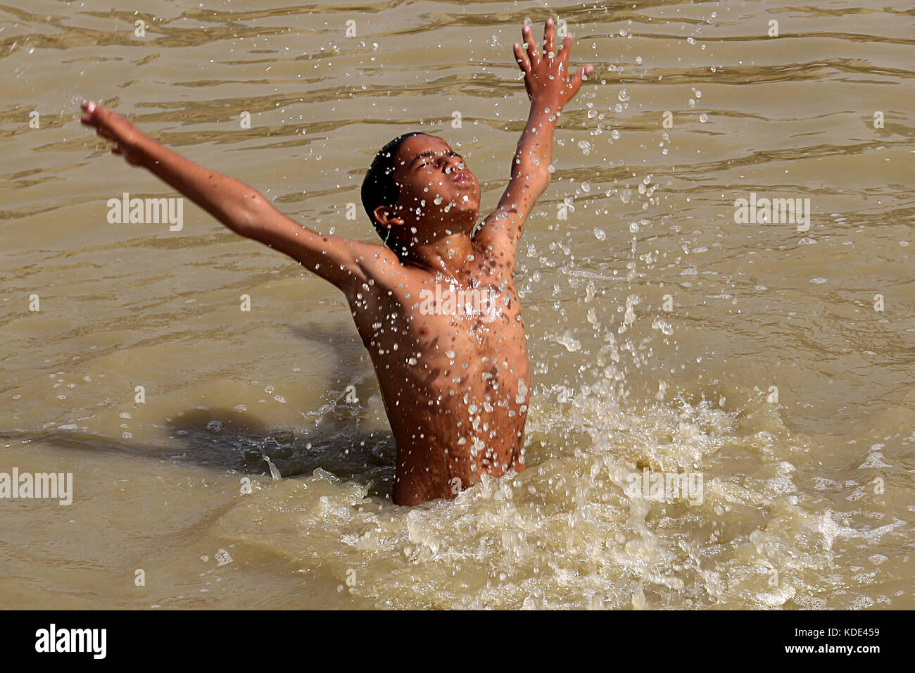 Karachi. 13 octobre 2017. Un garçon pakistanais se refroidit dans un canal d'eau alors que la température atteignait 42 degrés Celsius dans le sud du port pakistanais de Karachi le 13 octobre 2017. Crédit : Arshad/Xinhua/Alamy Live News Banque D'Images