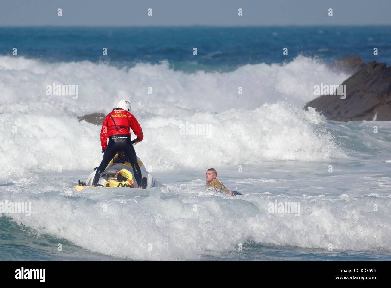 La plage de Fistral, Newquay, Cornwall, UK. 13 octobre, 2017. Les surfeurs prendre part au jour 1 de la chauffe et de la University College Sports la concurrence. Un internaute est aidé par le RNLI loin de la roche sur le côté nord de la plage. Banque D'Images