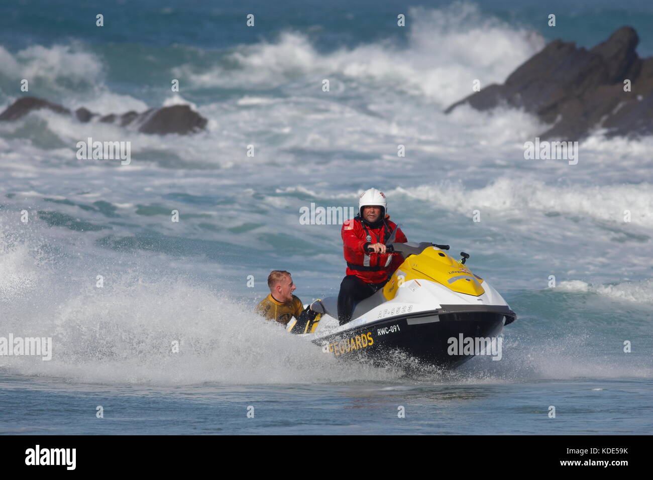 La plage de Fistral, Newquay, Cornwall, UK. 13 octobre, 2017. Les surfeurs prendre part au jour 1 de la chauffe et de la University College Sports la concurrence. Un internaute est aidé par le RNLI loin de la roche sur le côté nord de la plage. Banque D'Images