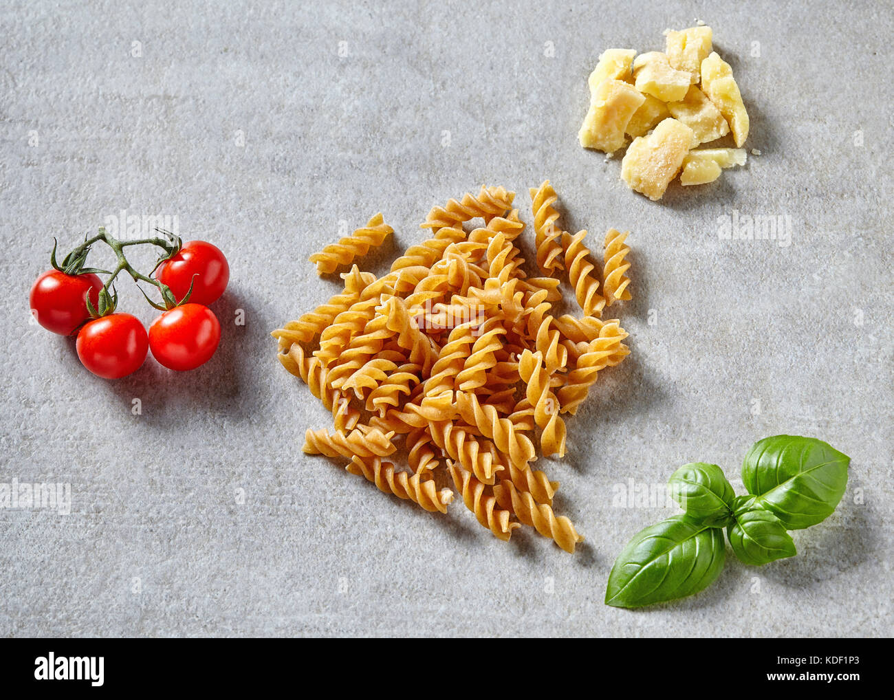 Les pâtes spaghetti, tomates, fromage, l'oignon, l'ail et les feuilles de basilic sur table en pierre grise Banque D'Images