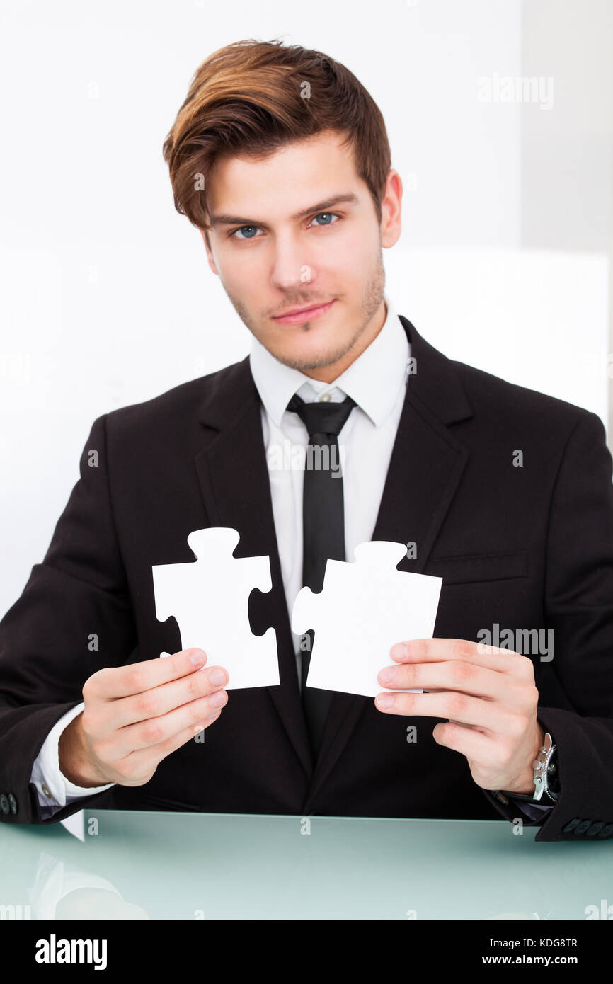 Portrait of a young businessman solving puzzle in office Banque D'Images