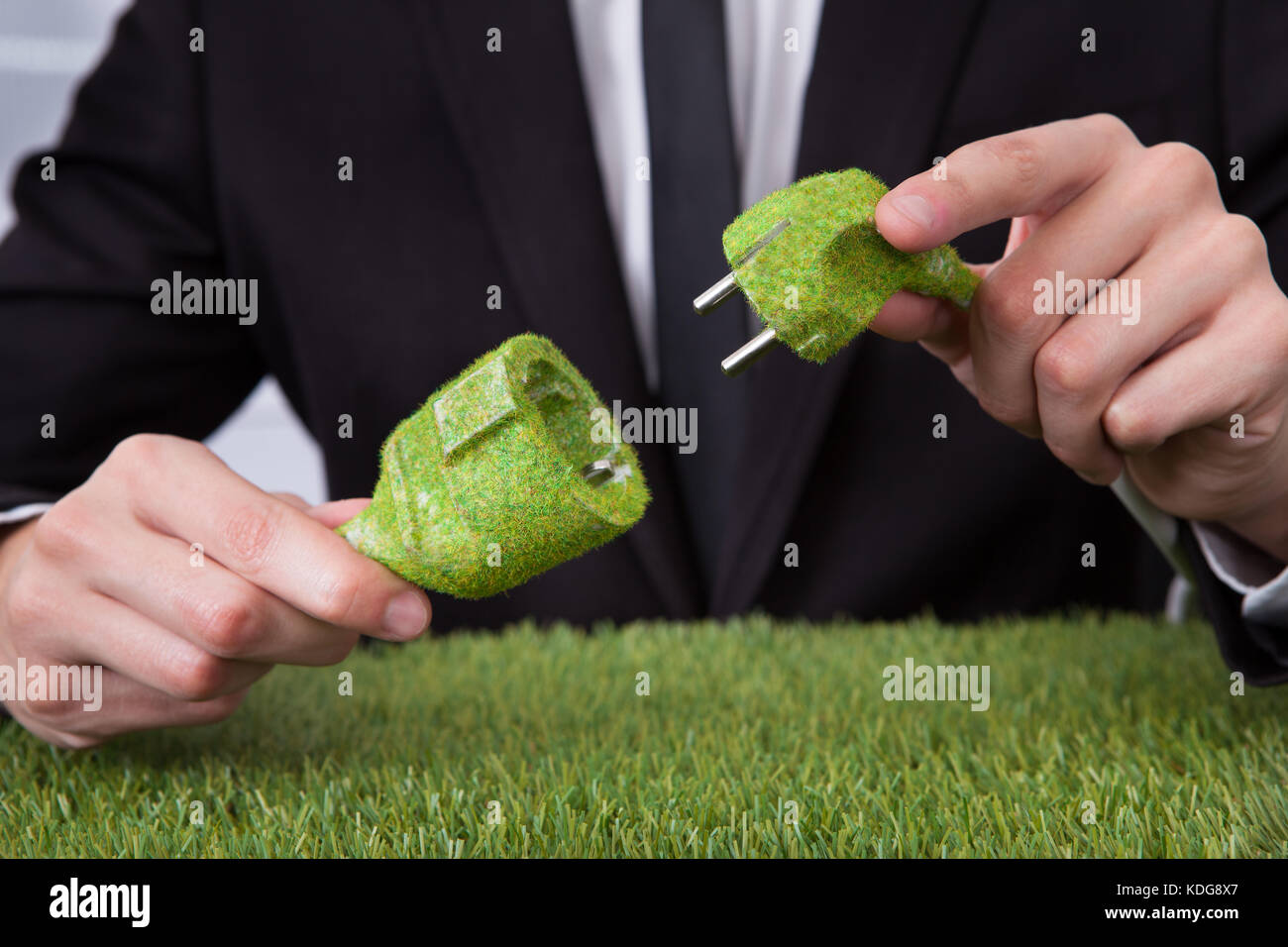 Close-up of businessman holding main couverte de graminées Fiche et prise électrique Banque D'Images