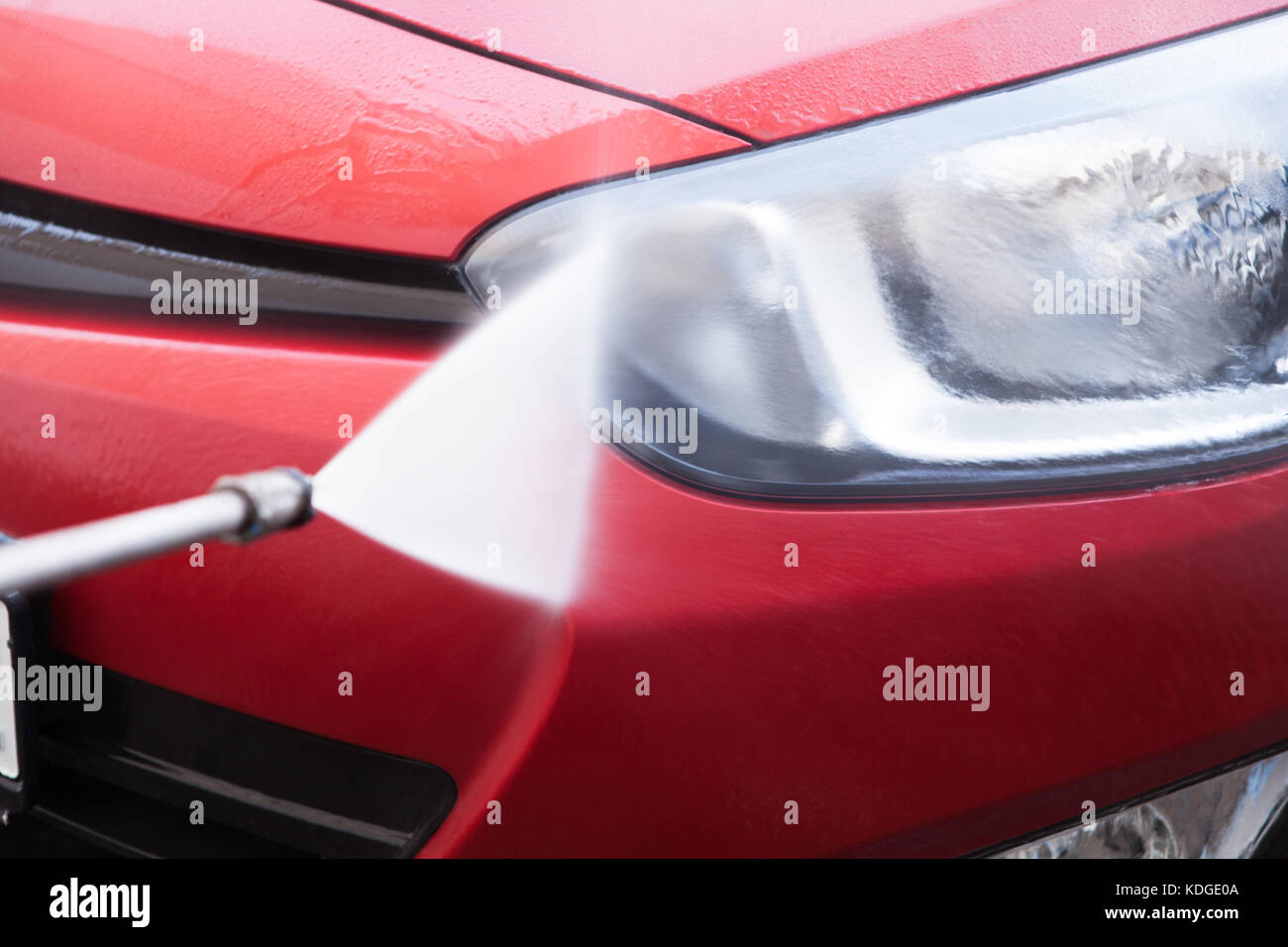 Close-up du flexible aux projections d'eau sur phare de voiture Banque D'Images