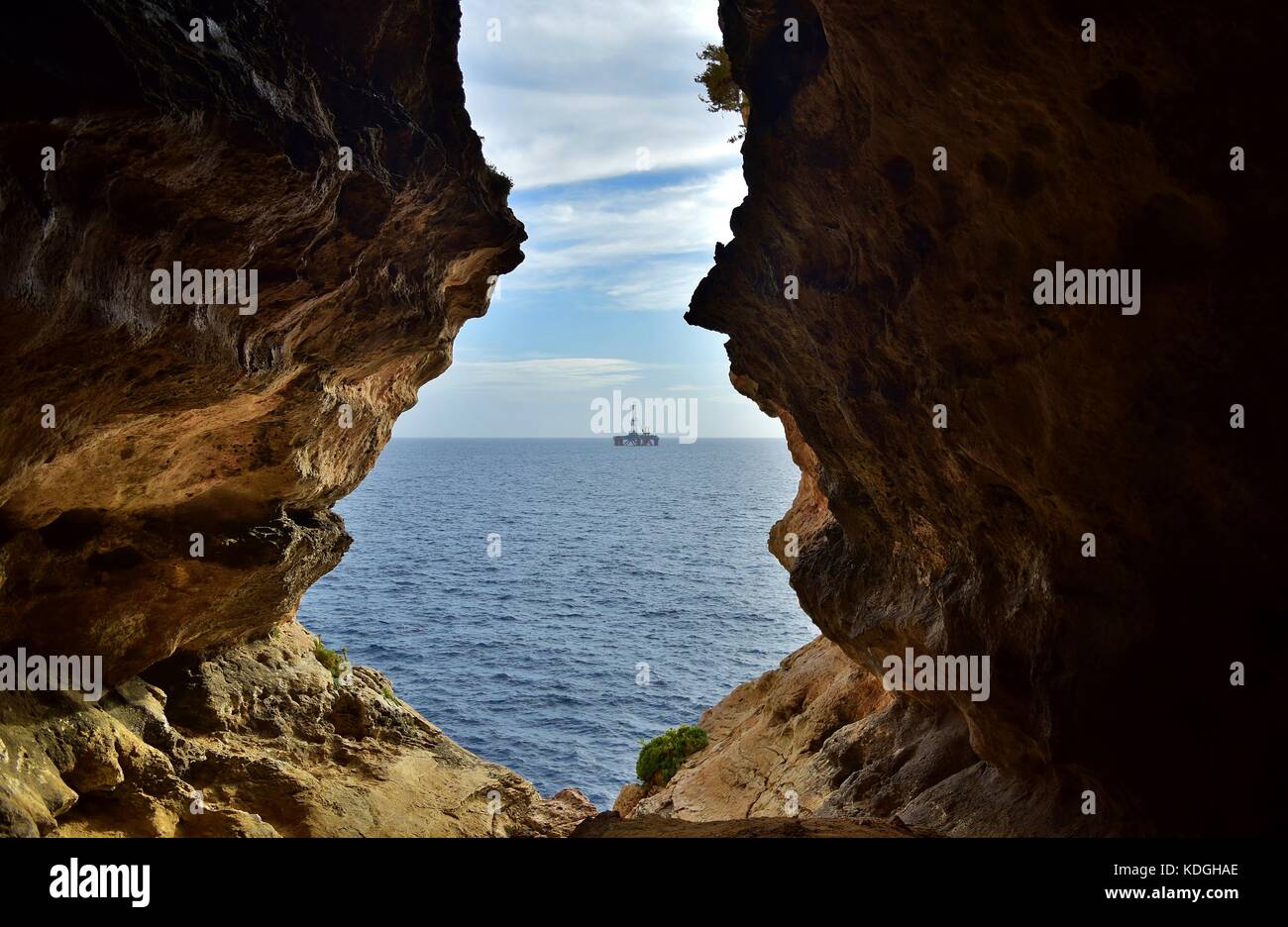 La vue de mer agitée, formé par l'érosion / érosion du calcaire maltais. La sortie de la grotte se trouve face à la mer, avec une plate-forme pétrolière dans la distance Banque D'Images