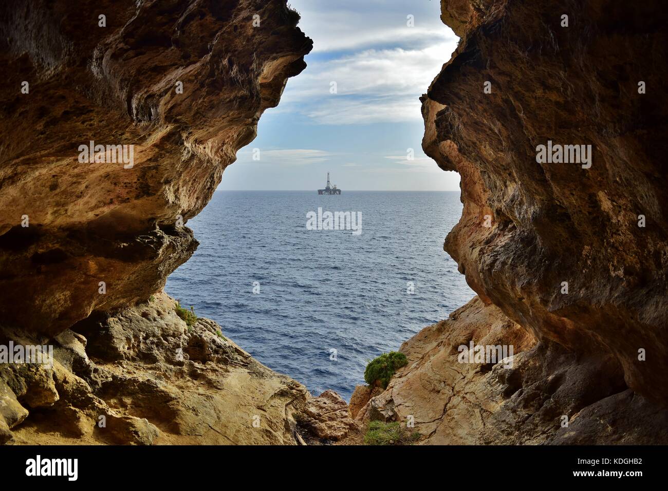 La vue de mer agitée, formé par l'érosion / érosion du calcaire maltais. La sortie de la grotte se trouve face à la mer, avec une plate-forme pétrolière dans la distance Banque D'Images