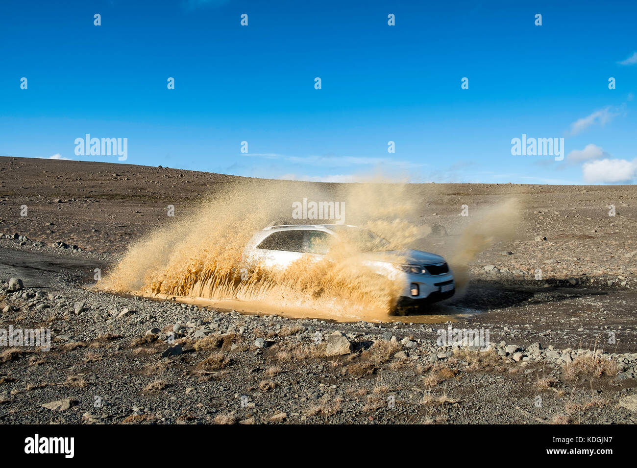 Voiture 4x4 roulant à vitesse dans un paysage désertique, sur le point d'unité dans un bassin d'eau sale, ciel bleu Banque D'Images