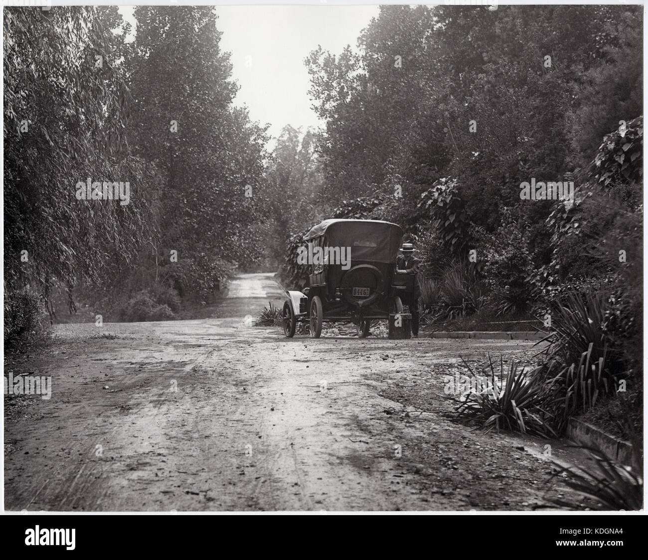 Homme debout à côté d'une voiture sur une route de terre non identifiés Banque D'Images