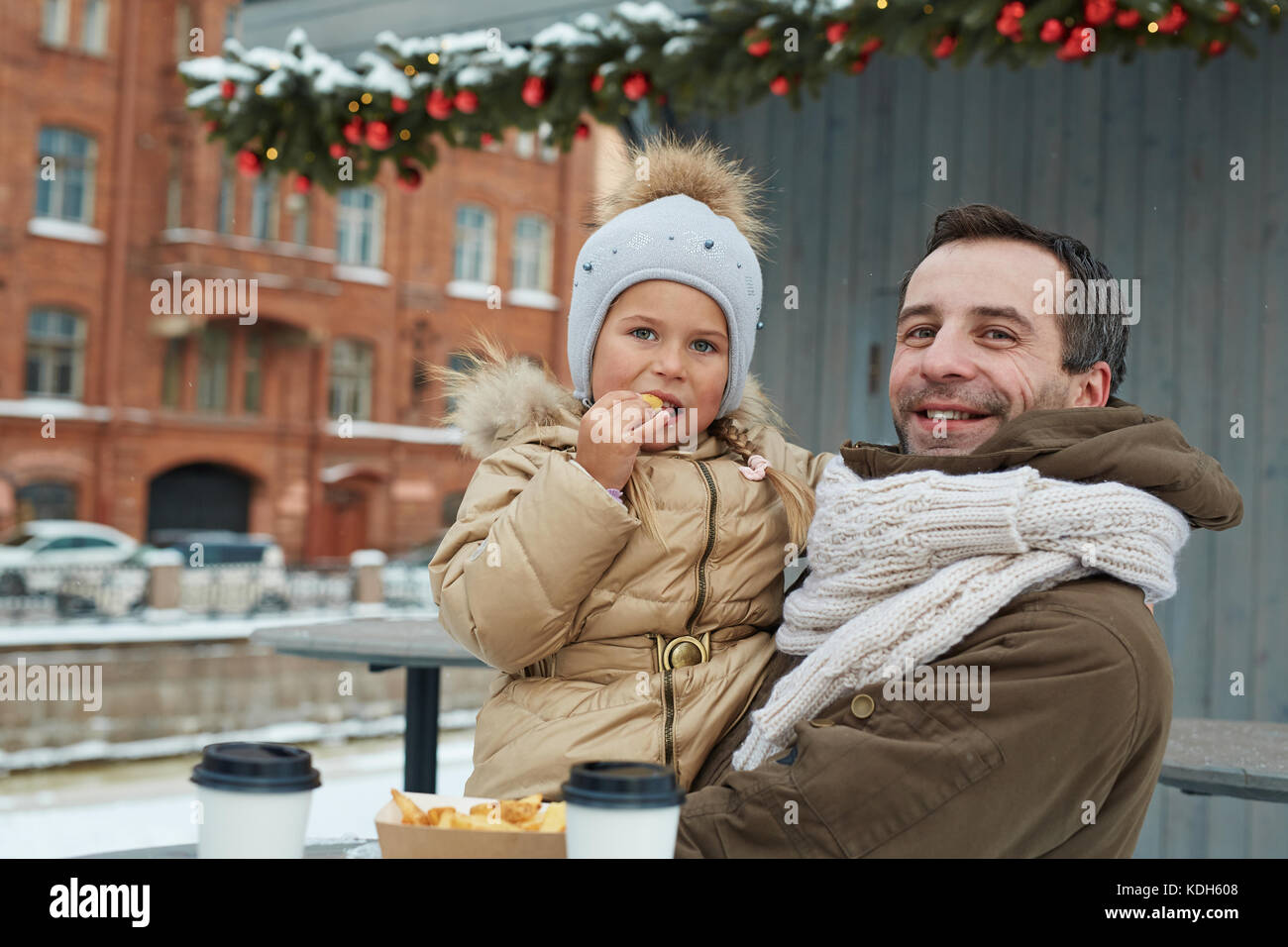 Hungry girl eating french fries sur son père hands outdoors Banque D'Images