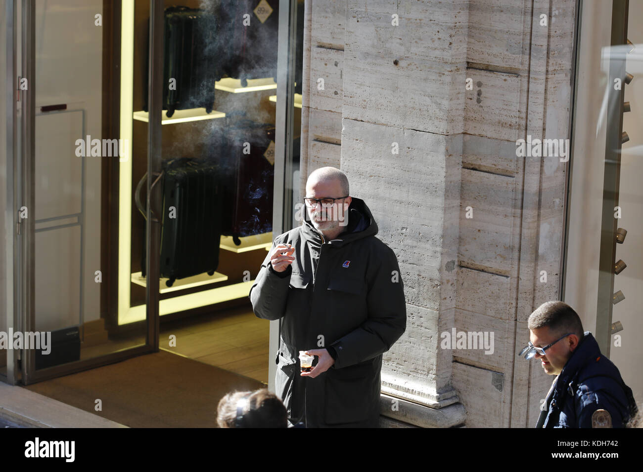 Homme qui fume à l'extérieur d'un bâtiment. Un nuage de fumée flotte dans l'air. Banque D'Images