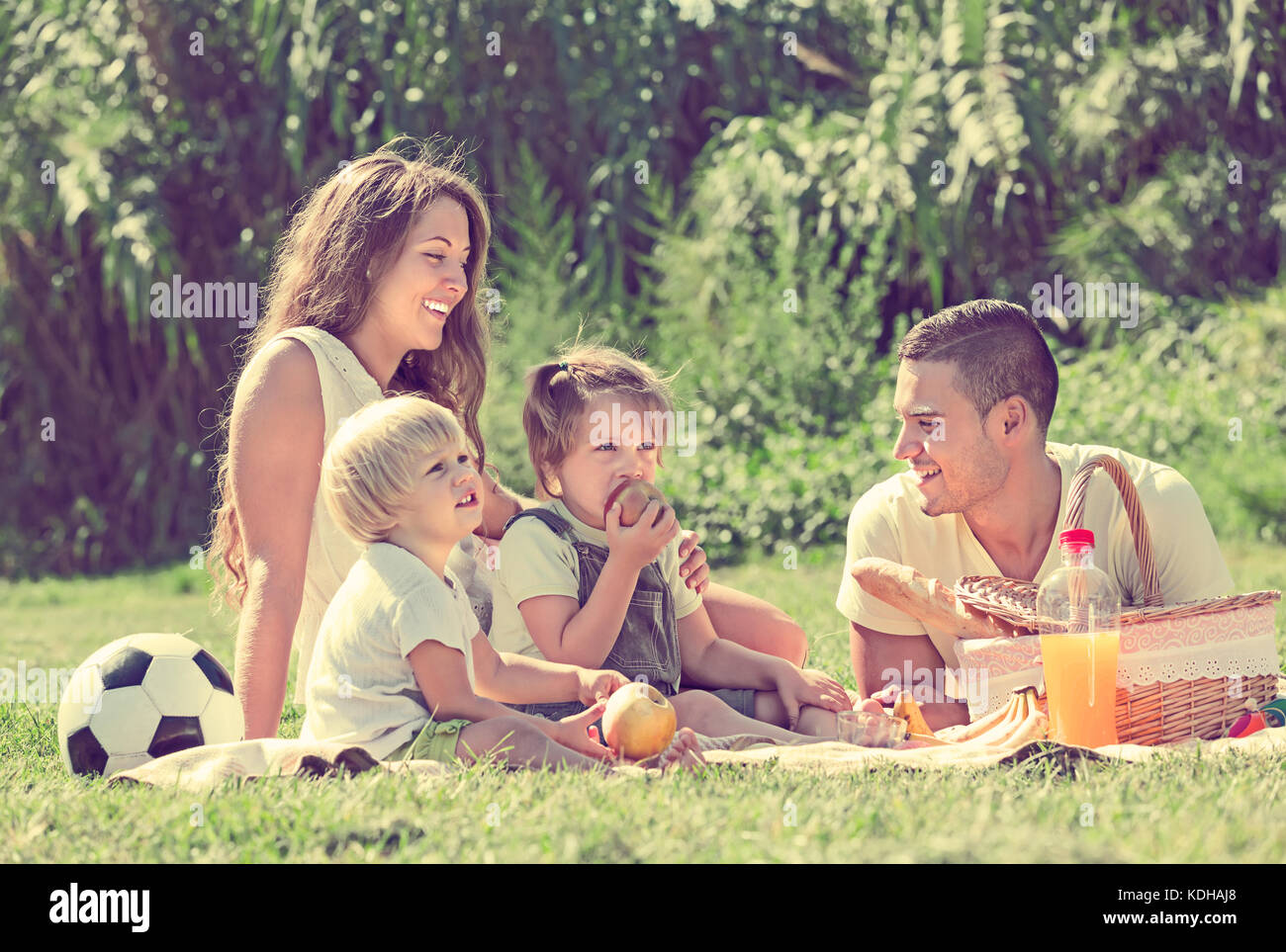 Souriante jeune famille de quatre having picnic à meadow en journée d'été Banque D'Images