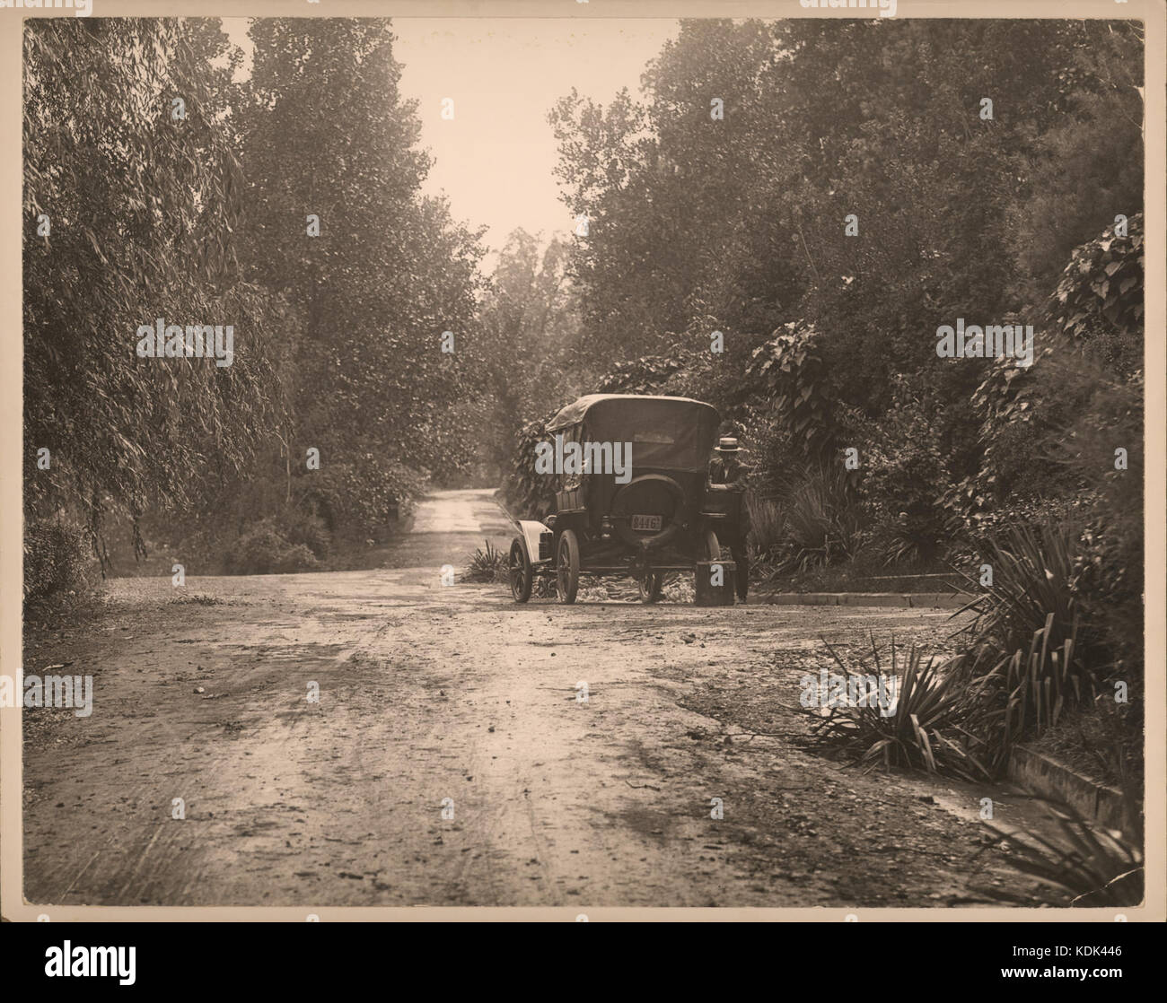Homme debout à côté d'automobile sur la route de banlieue non identifiés Banque D'Images