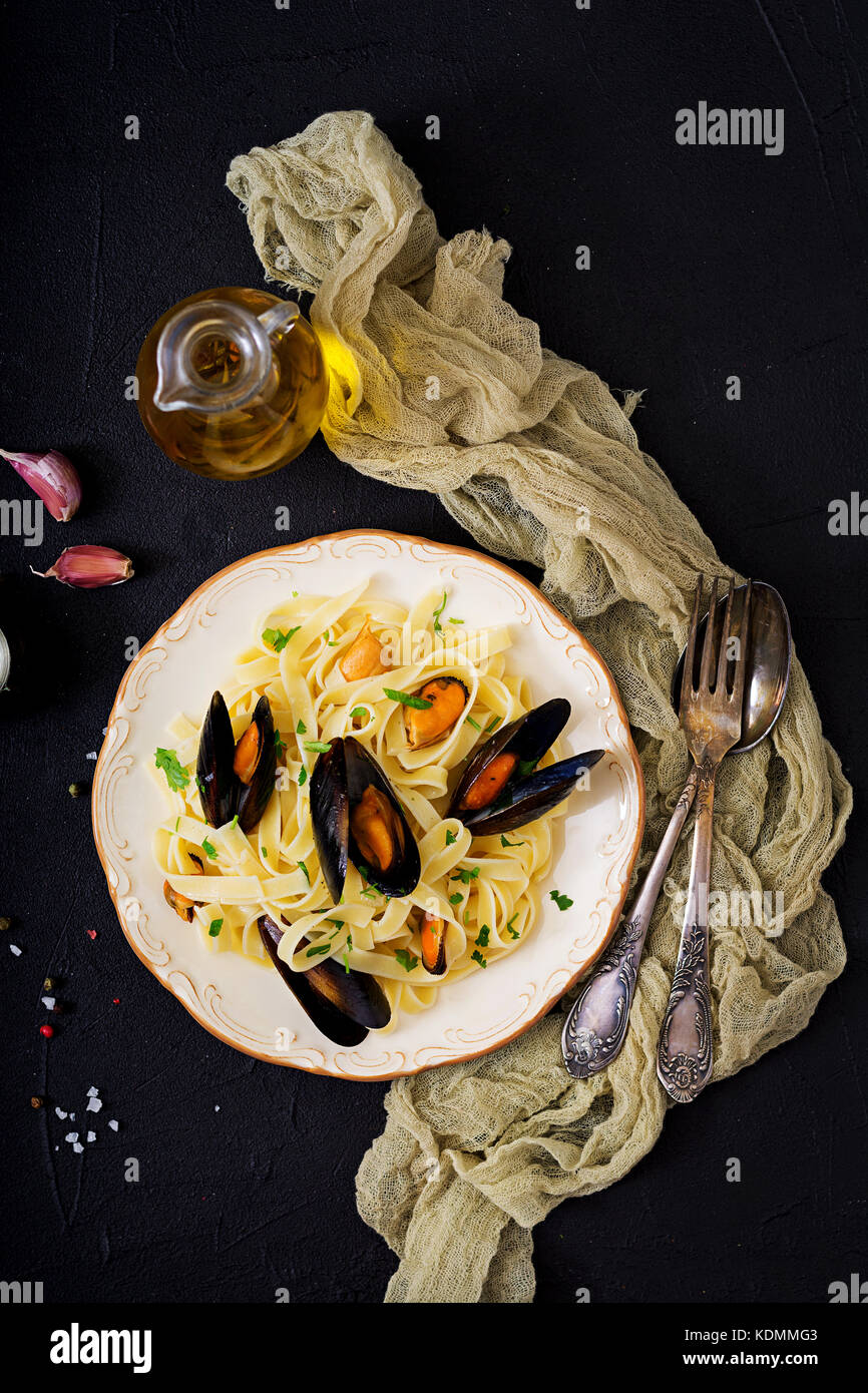 Fruits de mer pâtes fettuccine aux moules sur fond noir. délicatesse