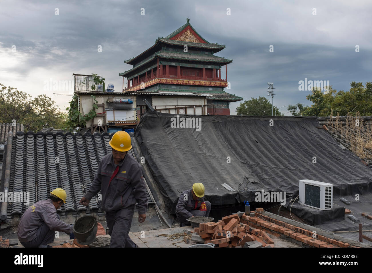 Les travailleurs qui appartiennent à l'autorité de logement de restaurer une vieille maison en face de la tour du tambour à Beijing, Chine. Banque D'Images