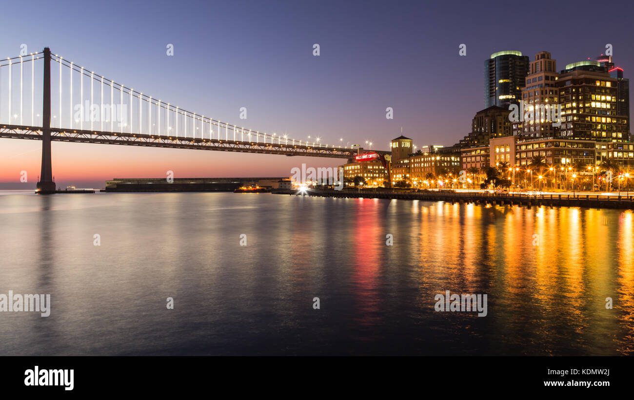 Réflexions de la San Francisco Bay Bridge et de pier 14 front de mer vue au lever du soleil. Banque D'Images