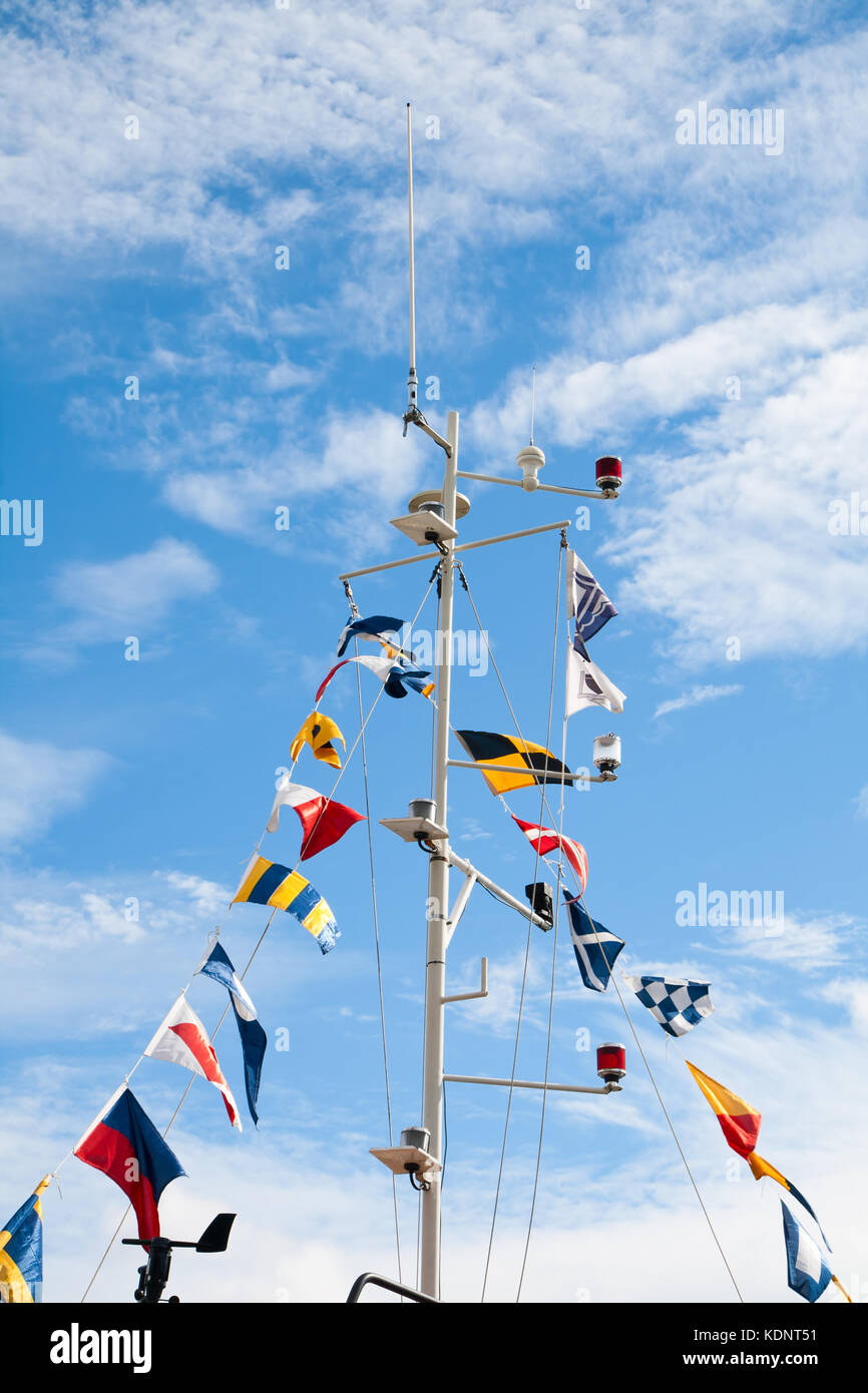 Mât avec signal nautique drapeaux contre le ciel bleu Banque D'Images