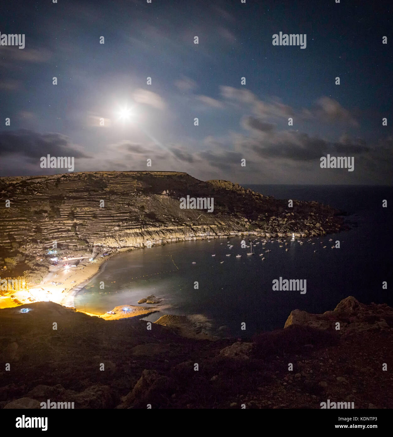 Une Lune gibbeuse se couche sur les falaises de gnejna bay à Malte Banque D'Images