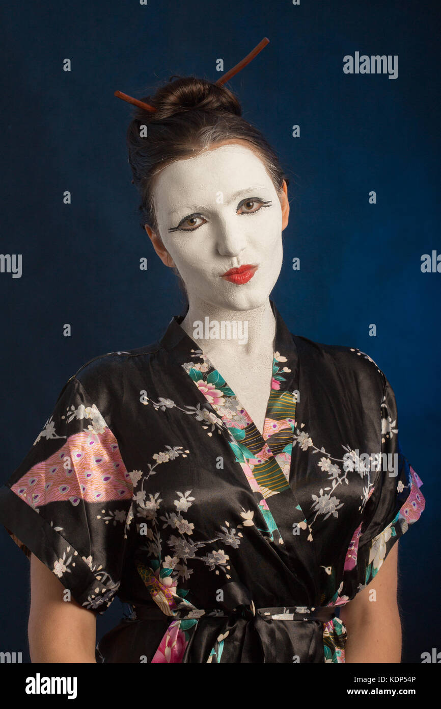 Fille en robe d'Asie avec blanc craquelé make-up sur fond bleu Banque D'Images