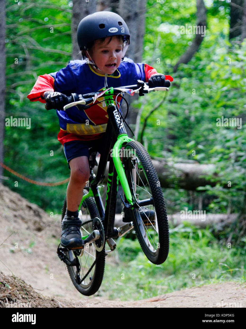 Un jeune garçon (5 ans) qui saute dans un vélo de montagne Banque D'Images