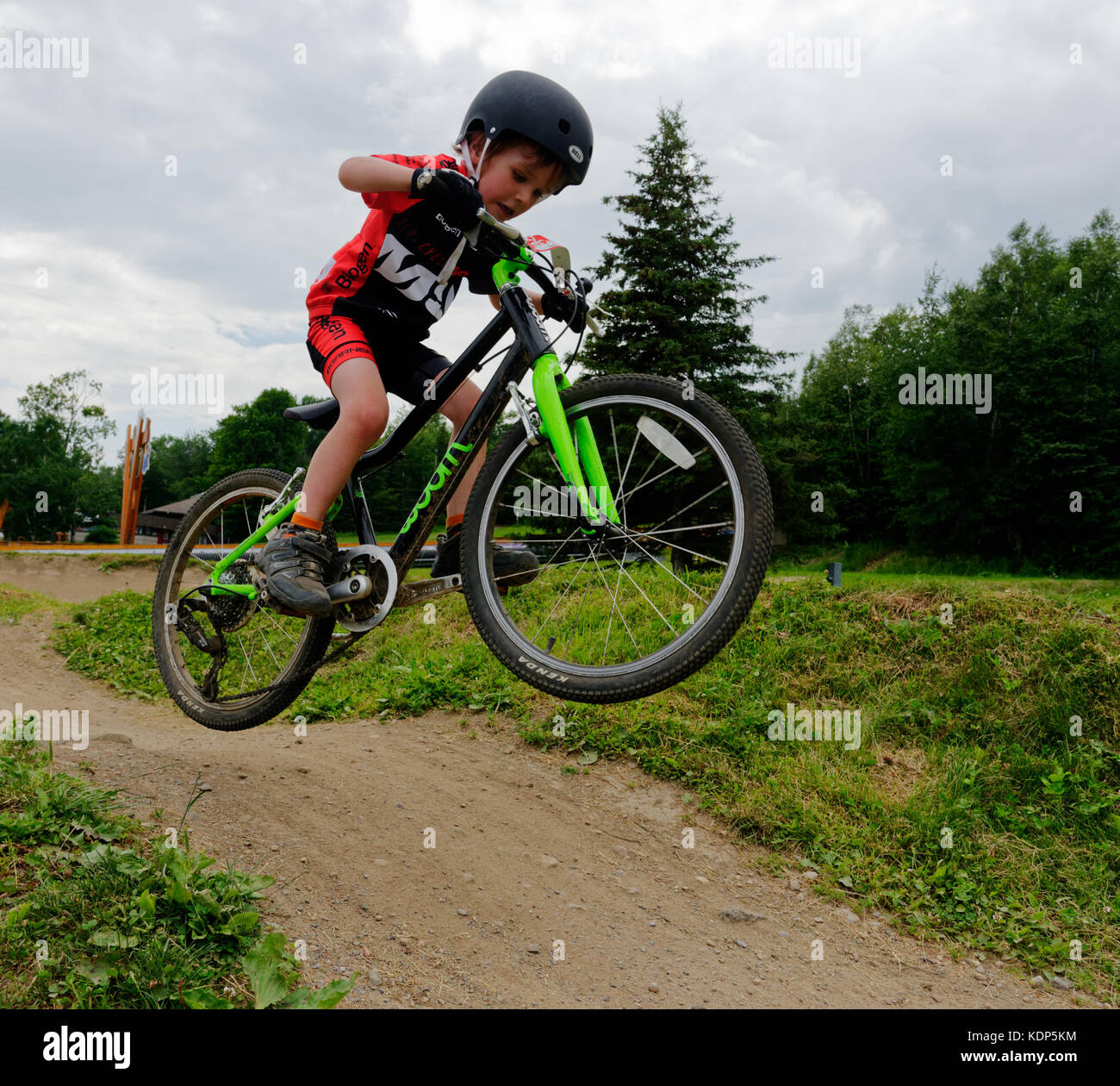 Un jeune garçon (5 ans) qui saute dans un vélo de montagne Banque D'Images