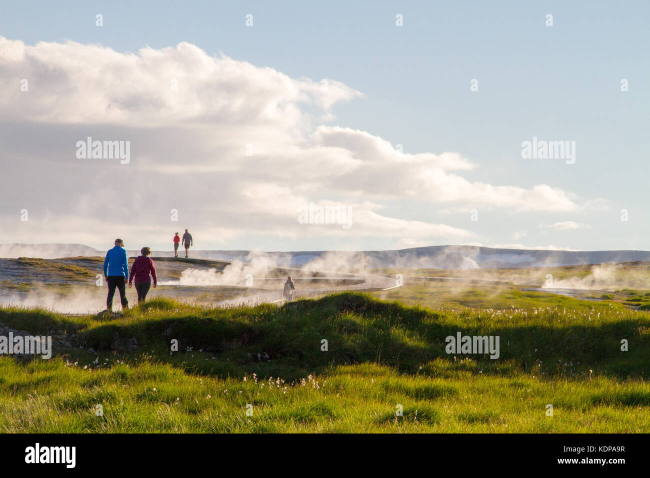 Couple walking through domaine des sources géothermiques à la fin de soleil du soir avec de la vapeur passant autour d'eux, de l'Islande Banque D'Images