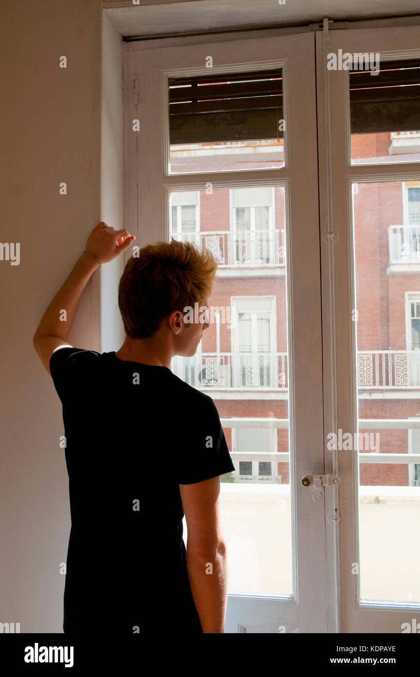Jeune homme regardant à travers la fenêtre. Banque D'Images