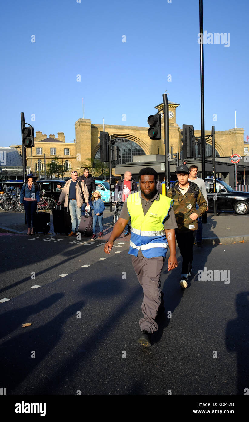 L'homme Afro Antillais en hi vis jacket croisement au passage piétons, Kings Cross, Islington, Londres, Angleterre Banque D'Images