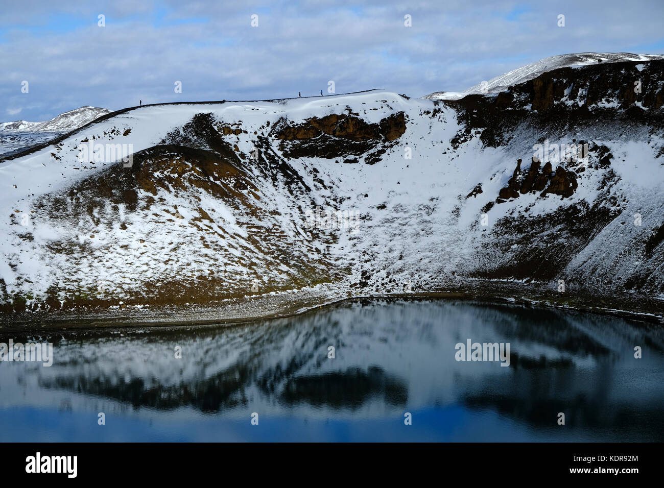 Neige et randonneurs sur le plateau du cratère d'explosion volcanique de Viti Krafla et le lac Aqua Blue dans la zone géothermique de Myvatnseldar, au nord de l'Islande Banque D'Images