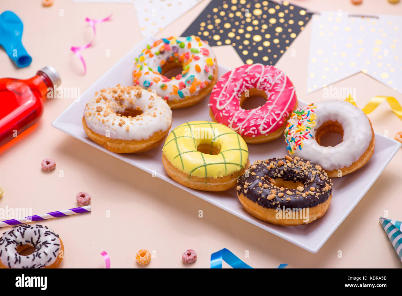 Partie vitrée ronde colorée. donuts et bouteilles de boissons sur fond rose. Banque D'Images