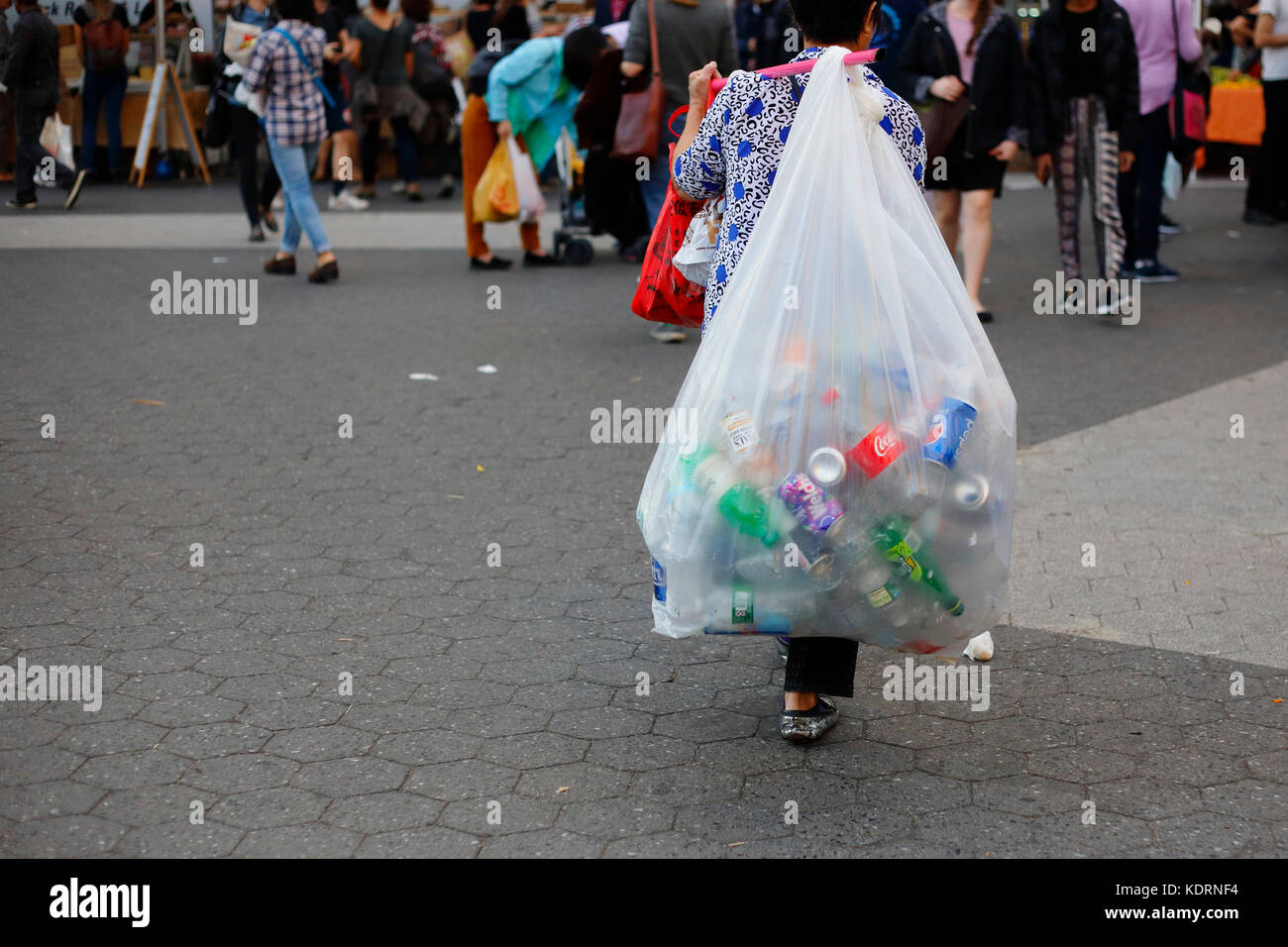 Une personne dans l'économie informelle portant un sac de bouteilles, bidons, et les matières recyclables. Banque D'Images