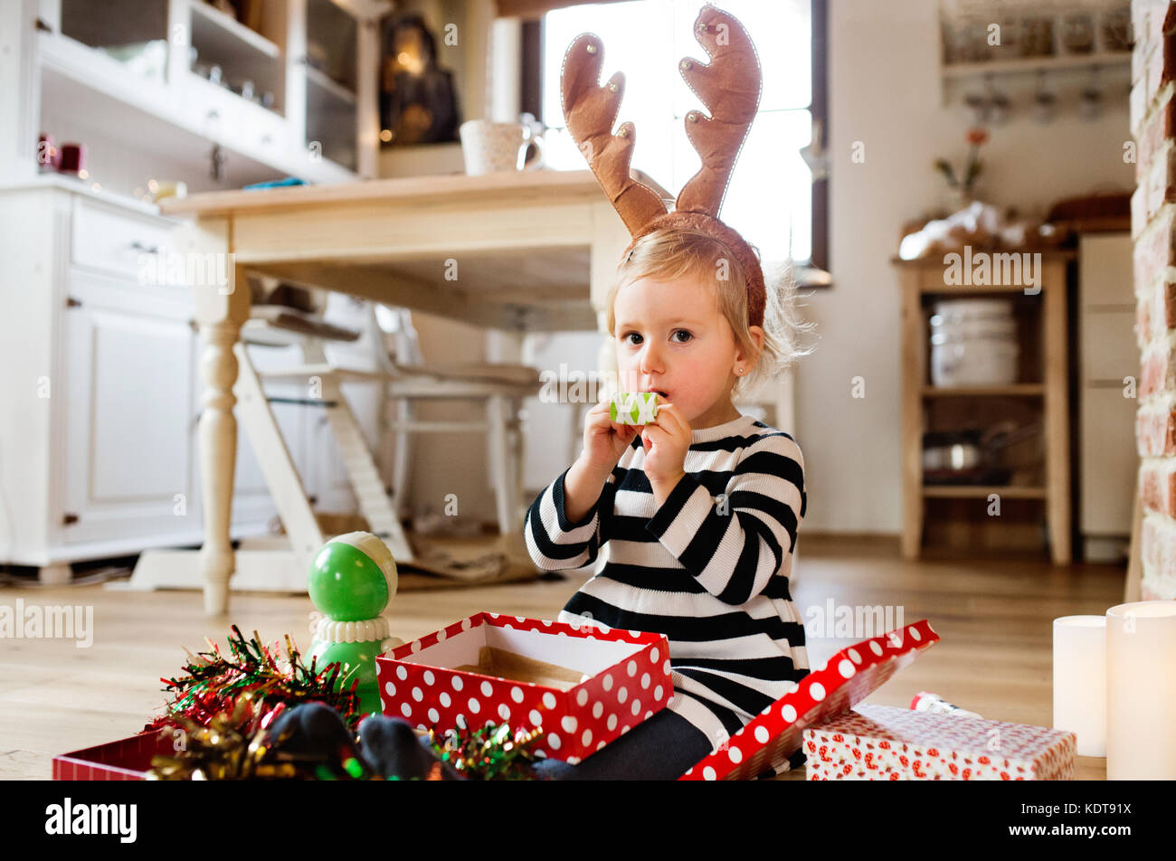 Cute little girl au moment de Noël, partie de soufflage de sifflets. fille wearing reindeer serre-tête. Banque D'Images