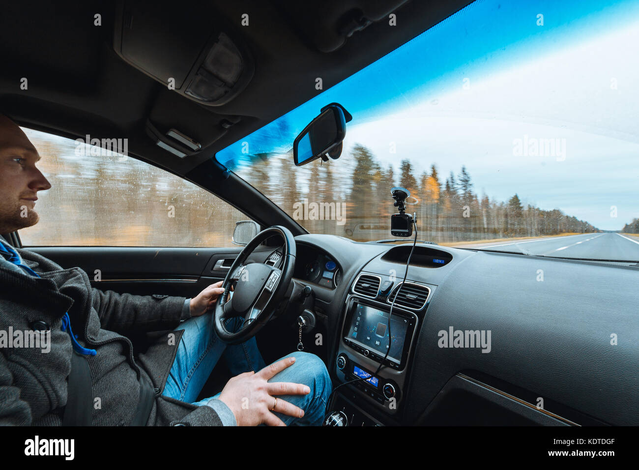 La main de l'homme conduisant une voiture à l'automne route entre forêt arbres homme s'asseoir à l'intérieur de contrôler le volume du système audio copie vide de l'espace pour l'inscription Banque D'Images