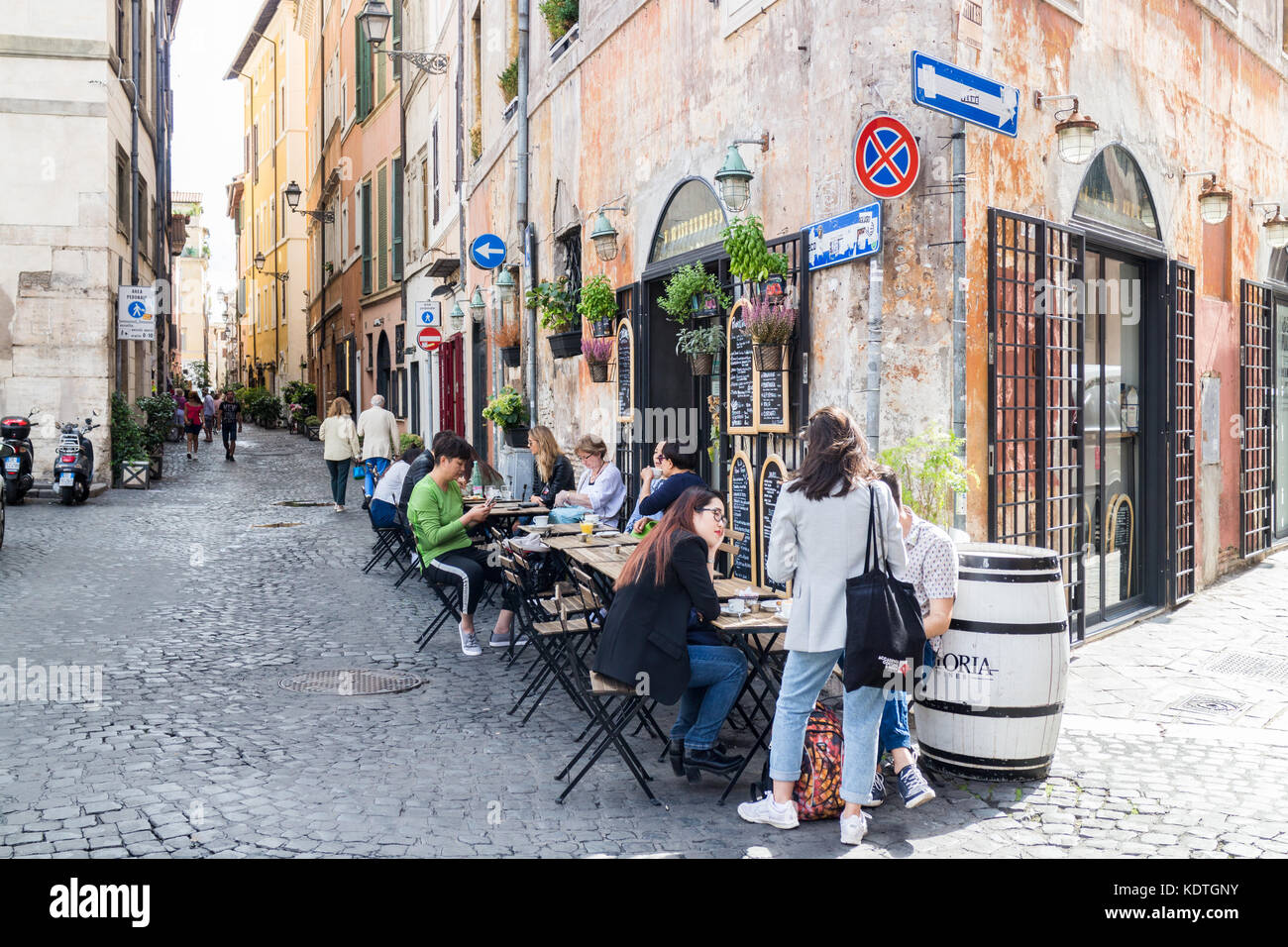 Les gens assis à des tables de restaurant dans une rue de Rome, Italie Banque D'Images