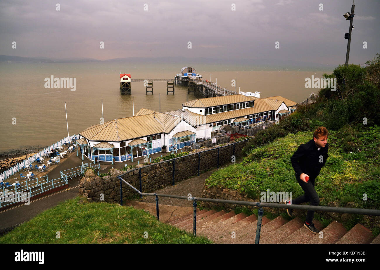 Un homme marche le pas de Mumbles jetée à la station village de Mumbles Banque D'Images