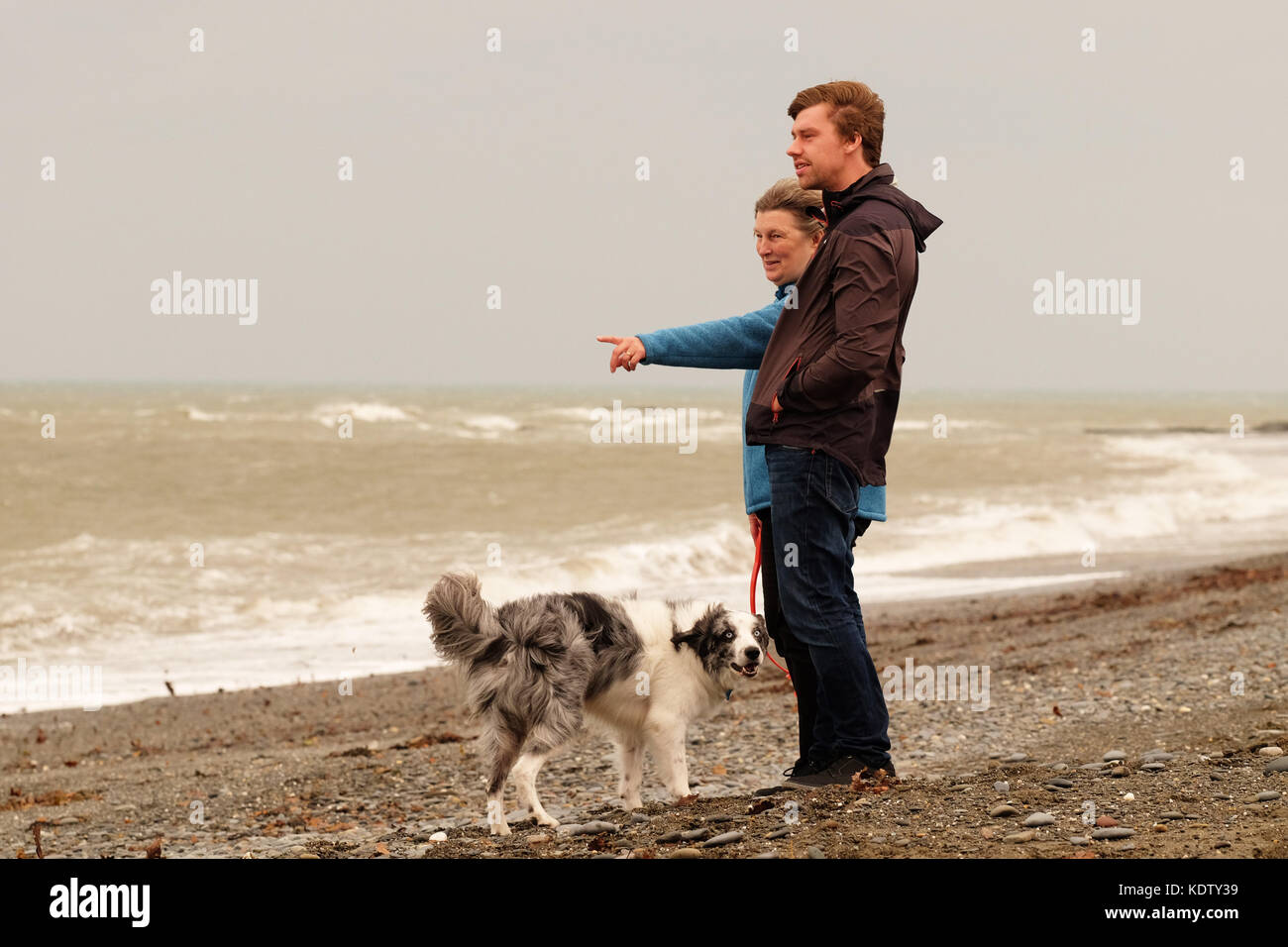 Aberystwyth, Ceredigion, pays de Galles, Royaume-Uni. 16 oct, 2017. uk weather. Des vents forts à l'ouest du pays de Galles à aberystwyth côte comme approches produisant une tempête ophelia teinte orange à la lumière qu'il porte haut le sable dans les nuages - les résidents de Lesley et Stephen pause sur leur chien à pied à regarder la tempête arrive au large de la mer d'irlande. crédit : Steven mai/Alamy live news Banque D'Images